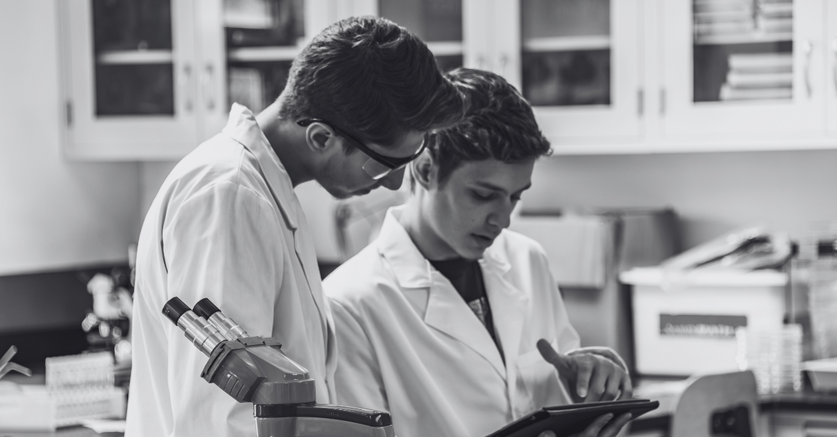 4 two lab techs looking at a tablet and discussing